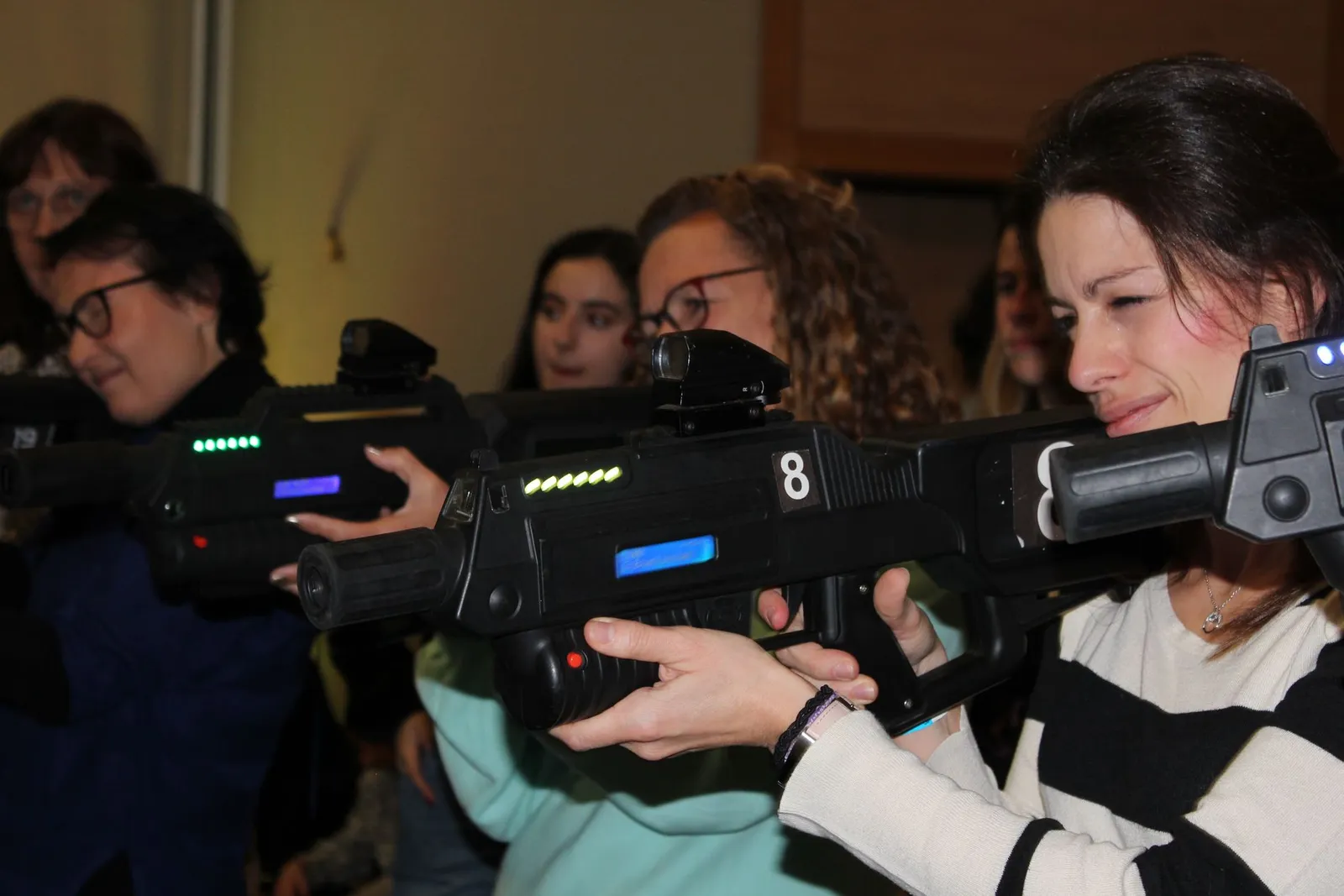 Des joueuses alignées, pistolet laser à l'épaule, pendant une partie de laser game