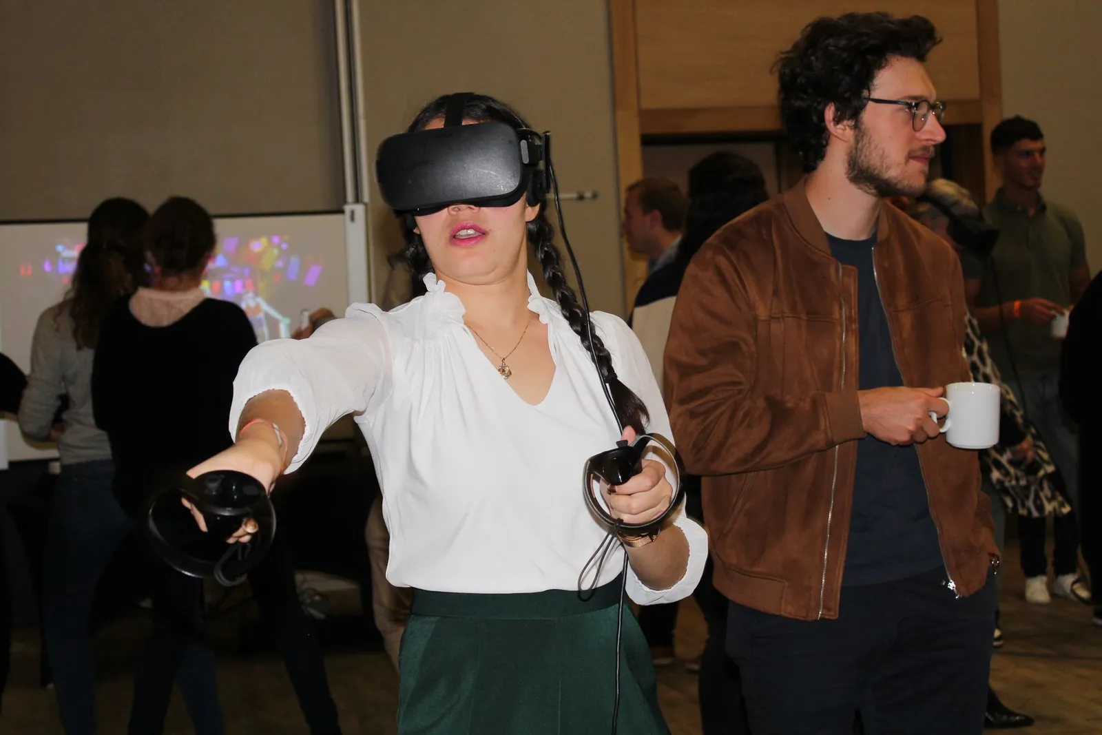 Une participante en casque de réalité virtuelle, manettes en main