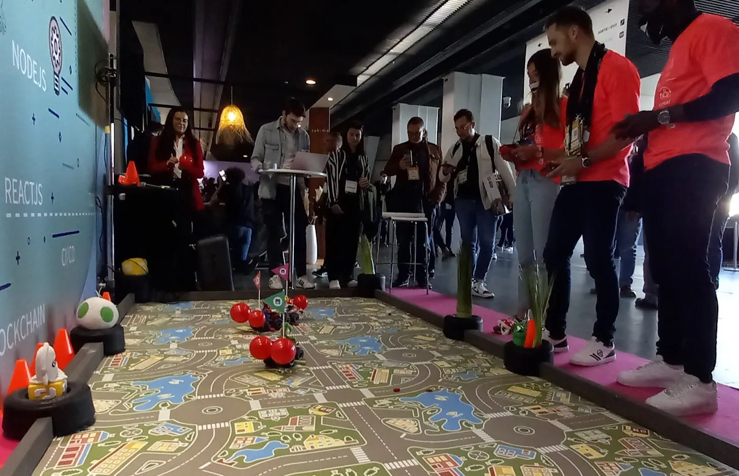 Circuit imprimé au sol avec cônes et karts radiocommandés, participants alignés le long du parcours