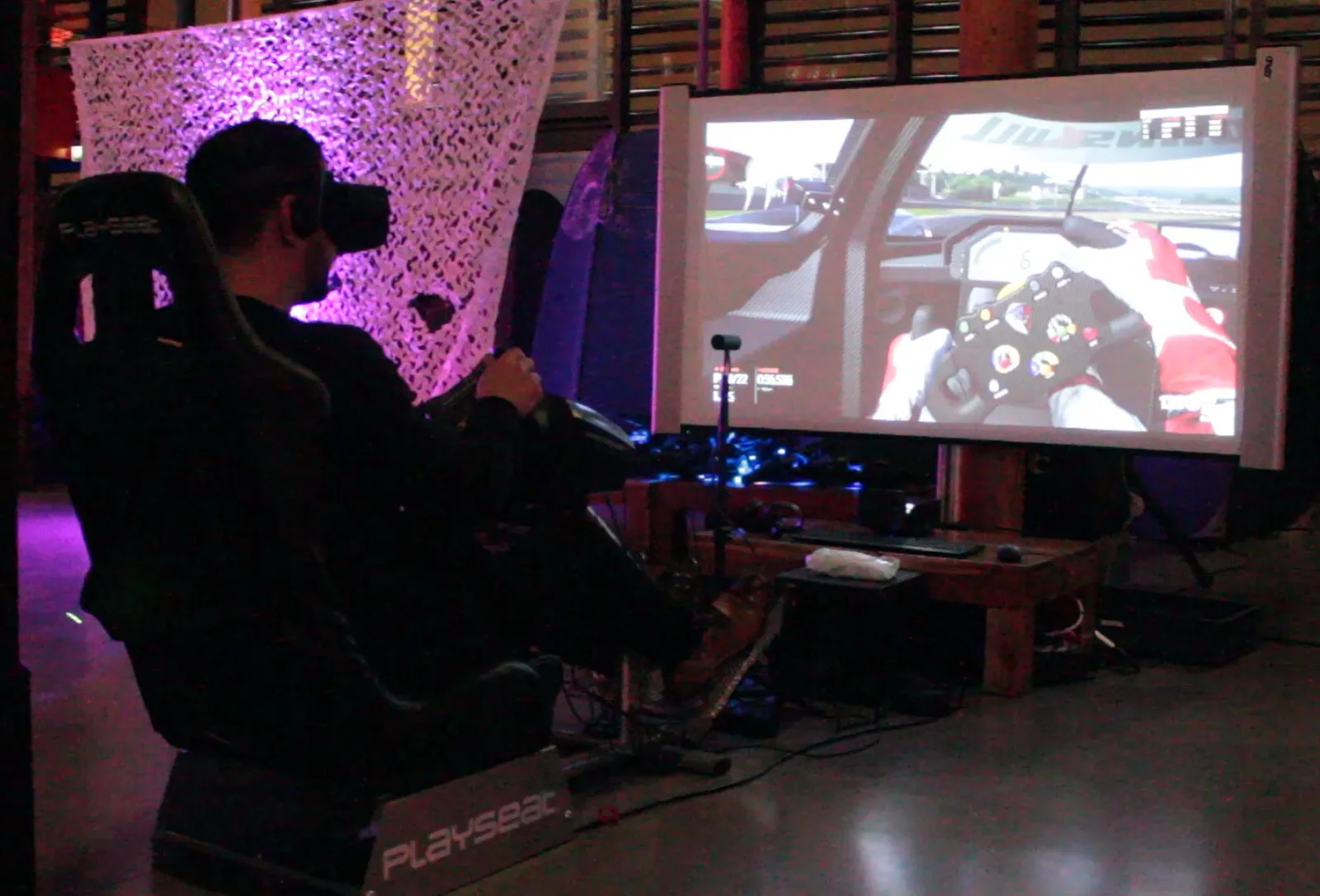 Participant en casque de réalité virtuelle dans un baquet, la course projetée sur un grand écran
