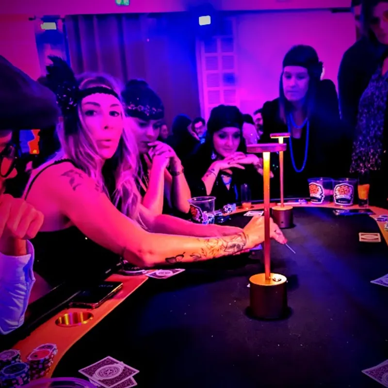Joueuse et invités autour d'une table de casino, lumière violette